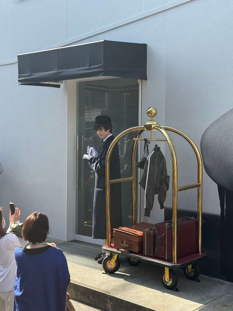 Close-up of the bellhop and brass luggage cart with vintage suitcases at the Adidas pop-up